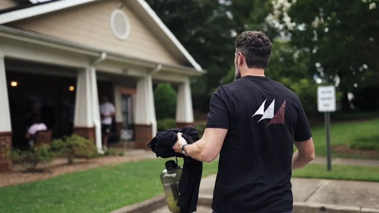 A man in an Armada Law shirt walking toward a brick porch