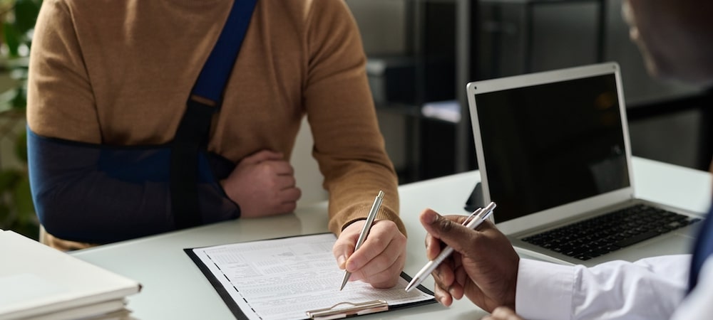 Two people are writing on a document at a table.