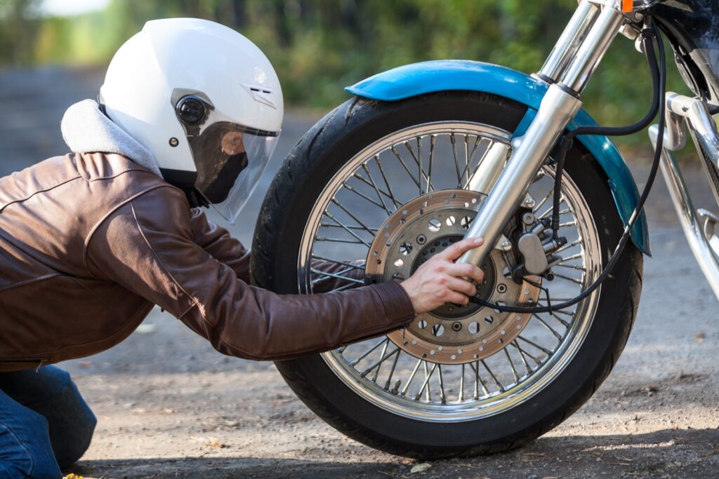 Motorcycle rider with helmet on fixing his bike
