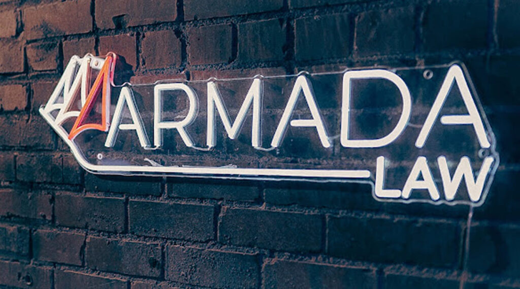 A white sign reading Armada Law is mounted on a dark brick wall.