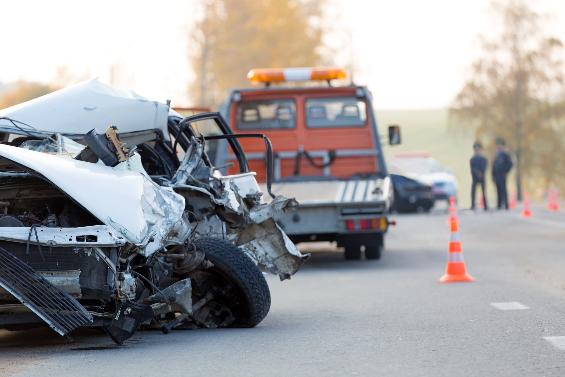 Dos coches chocados en una carretera con un vehículo de emergencia al fondo