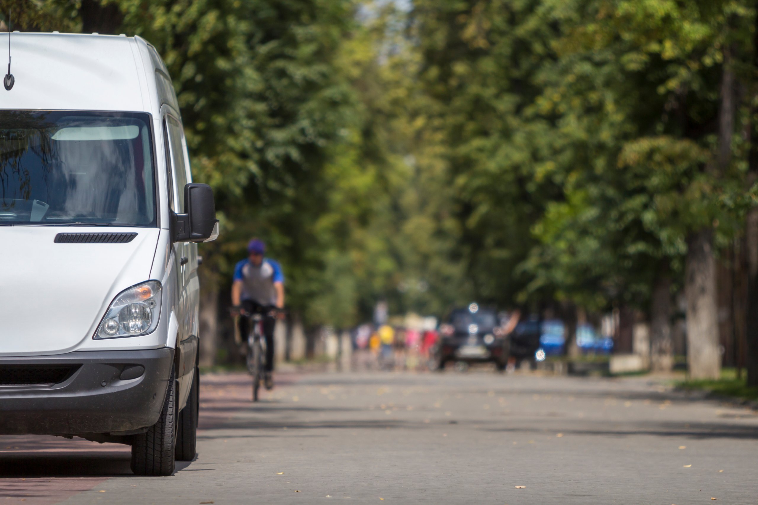 White amazzon delivery vehicle on the street next to a cyclist
