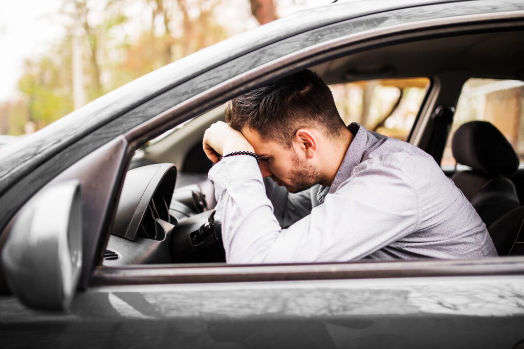 A man rests his head on his hand while sitting in a car.