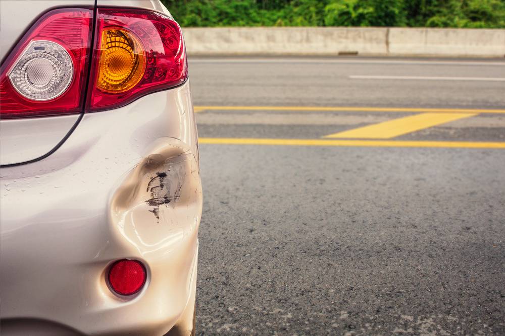 A dent is visible on the rear bumper of a car.