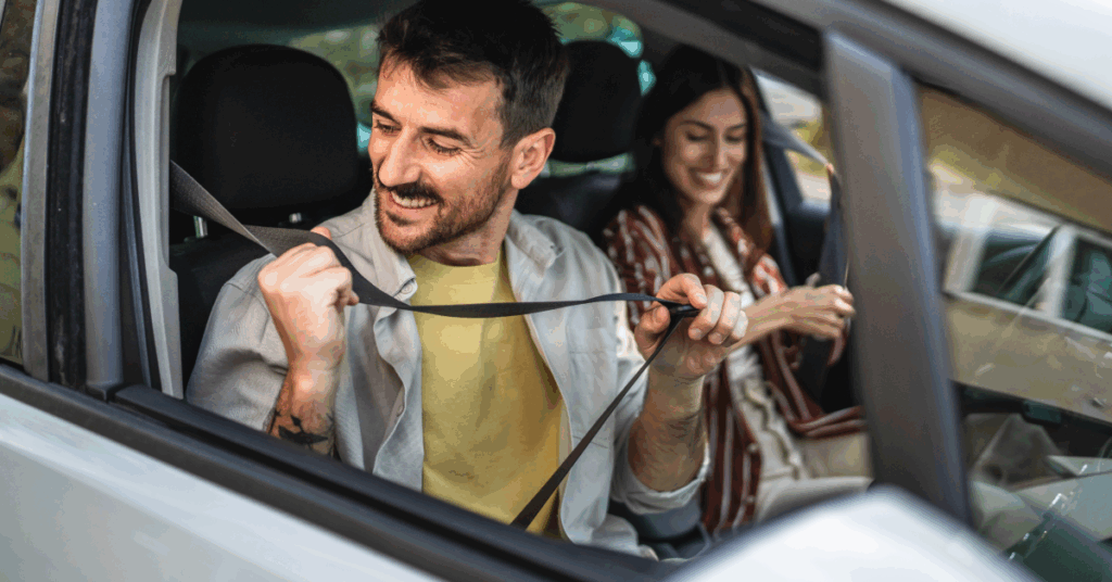 A man and woman are sitting in a car holding a strap.
