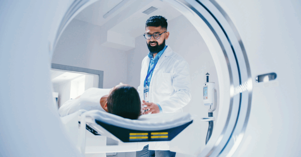 A doctor in a white coat looks at a patient lying on an examination table.