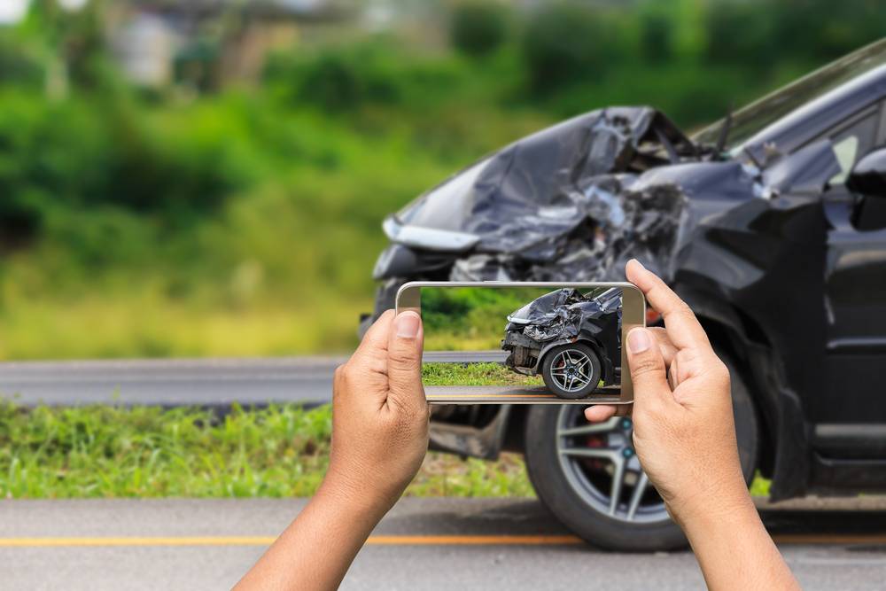 Person taking photo of crashed car for insurance claim