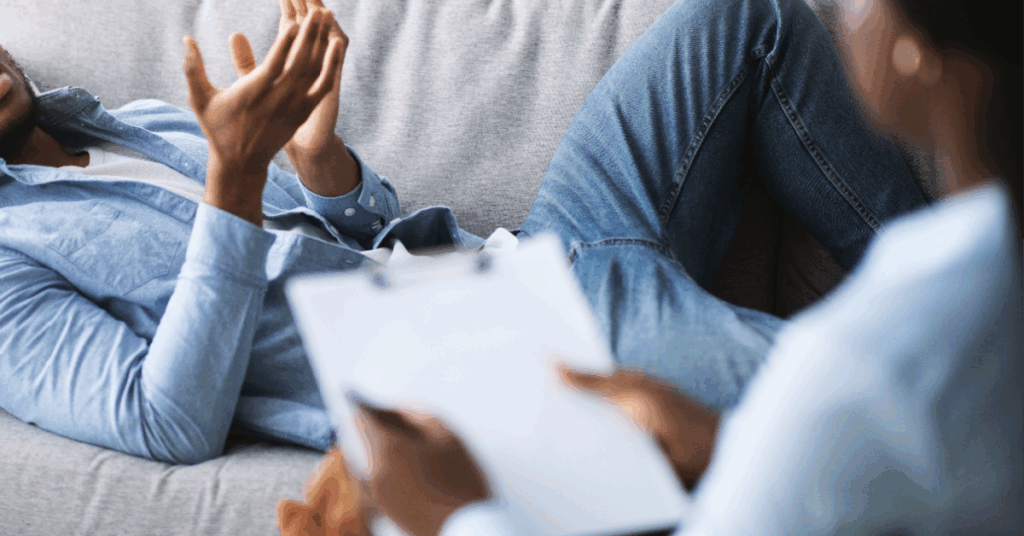 Hands are resting on papers while sitting on a couch.