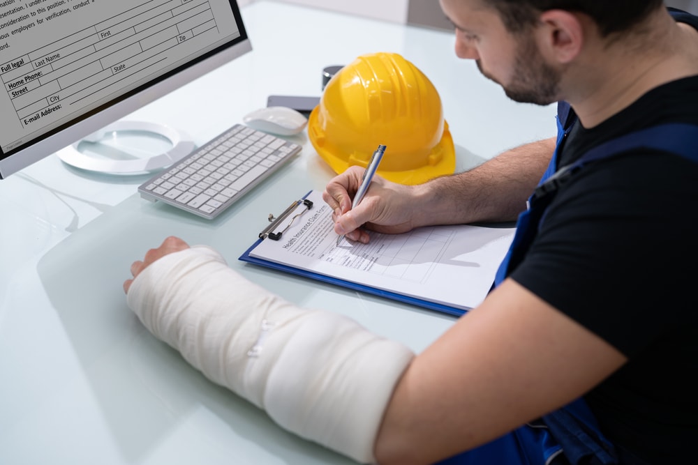 Worker with injured arm filling out workers comp form