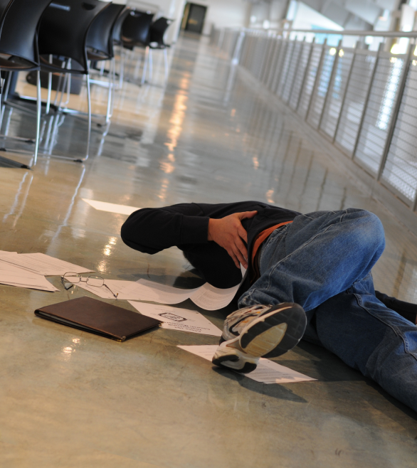 man holding his back after falling and slipping on the ground in a business