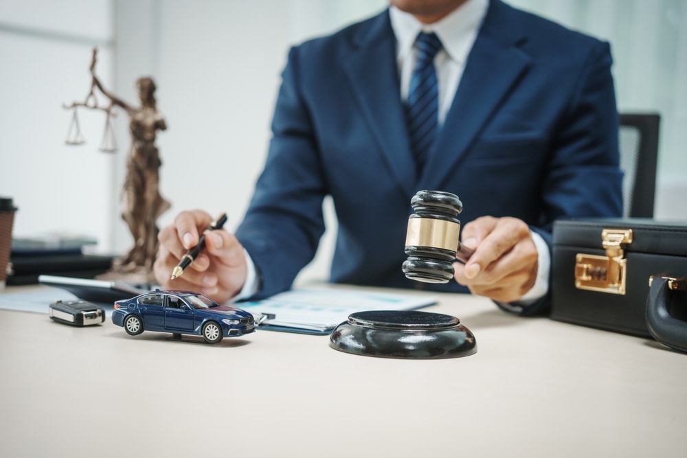 Car accident lawyer with gavel in hand and toy car on desk
