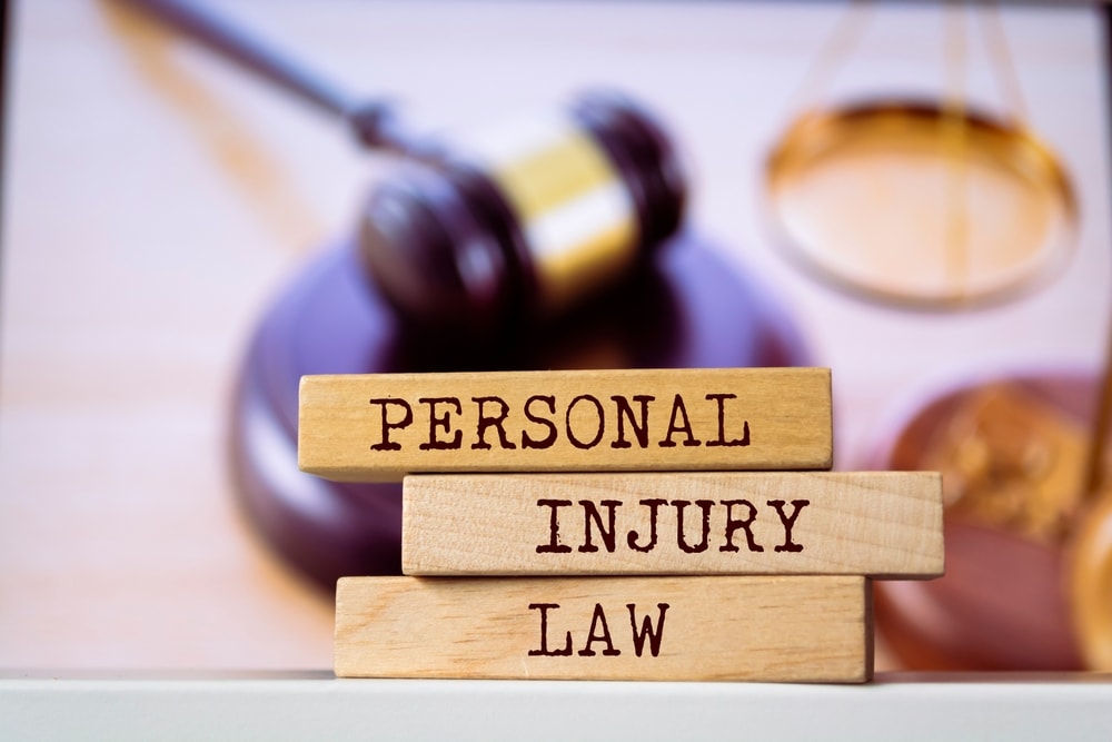 Closeup of the phrase "Personal Injury Law" printed on wooden blocks with a gavel in the background