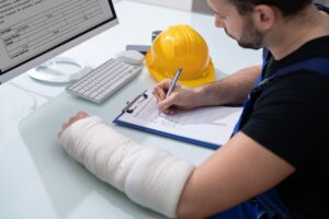 Worker with injured arm filling out workers comp form