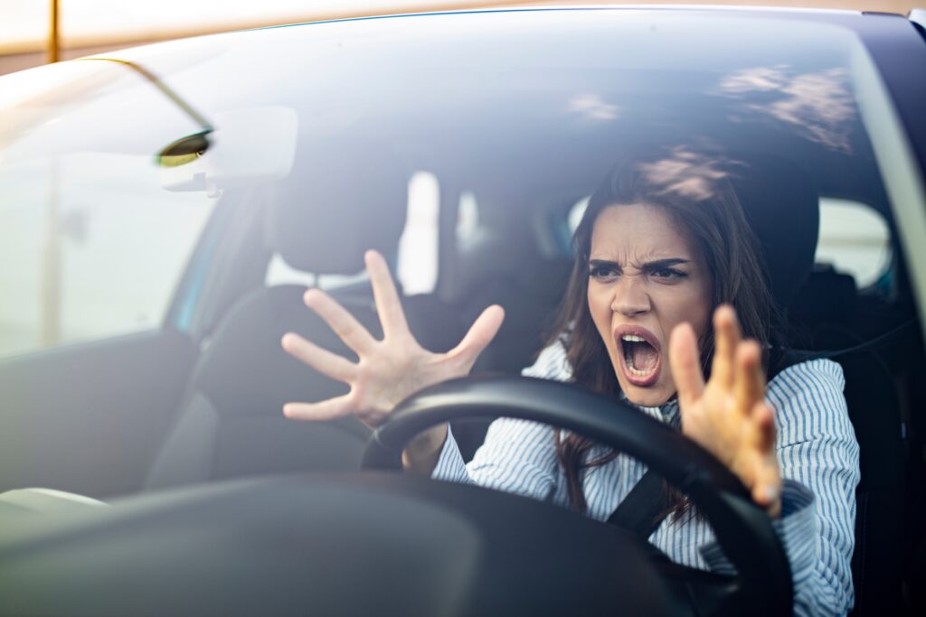 Angry reckless woman behind strearing wheel