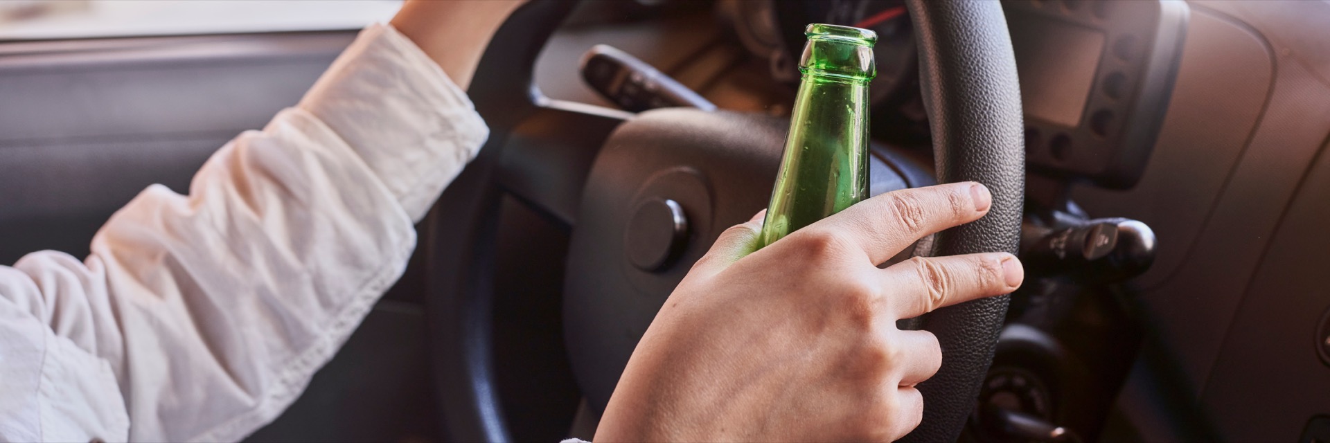 Person drinking and driving while holding bottle